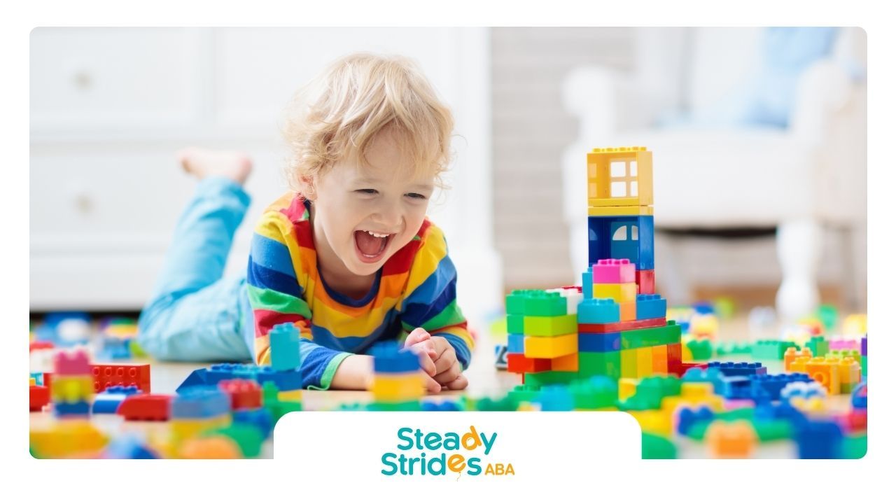 A young boy is laying on the floor playing with lego blocks.