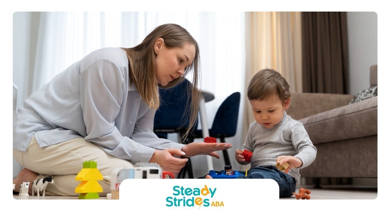 ABA therapist is sitting on the floor playing with a baby.