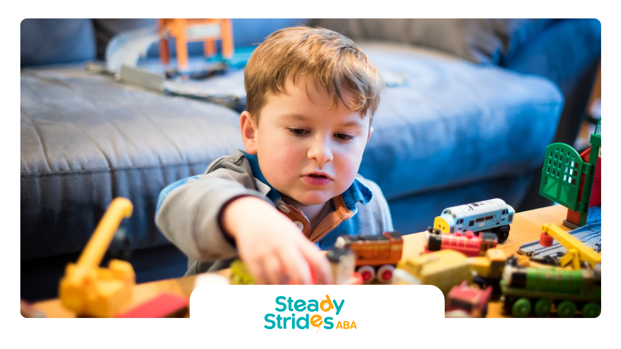 A young boy is playing with a toy train set on a table.