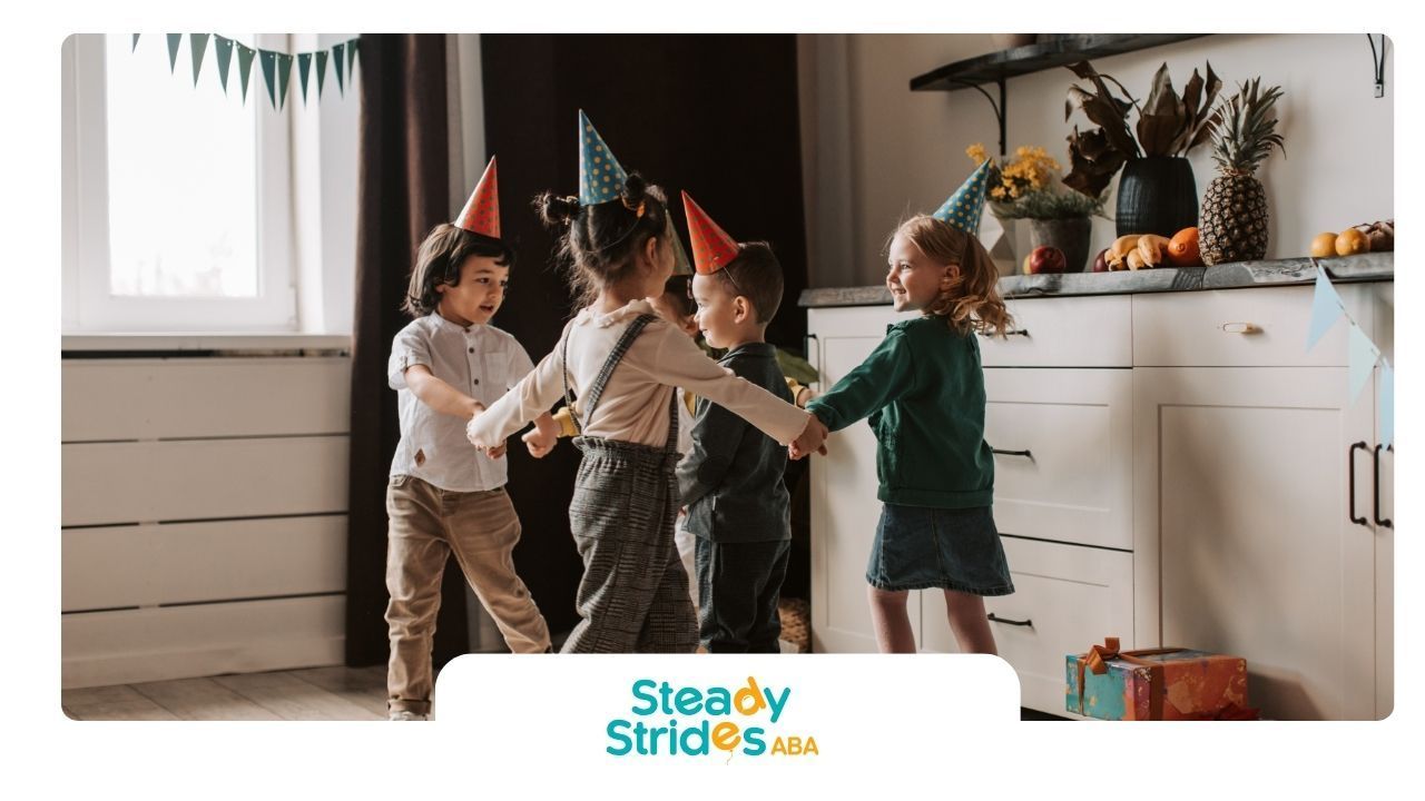 Children in party hats dance in a kitchen.