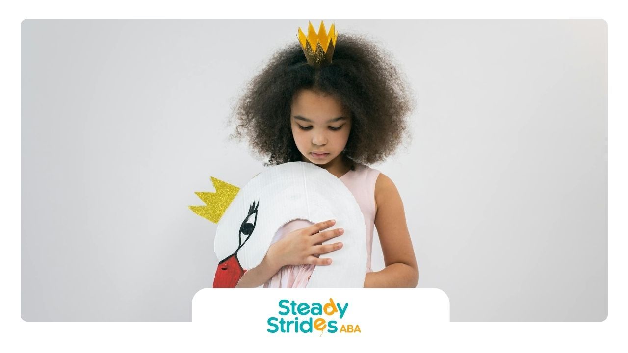 Autistic girl wearing a crown holding a swan costume, avoiding eye contact during ABA therapy in TX.