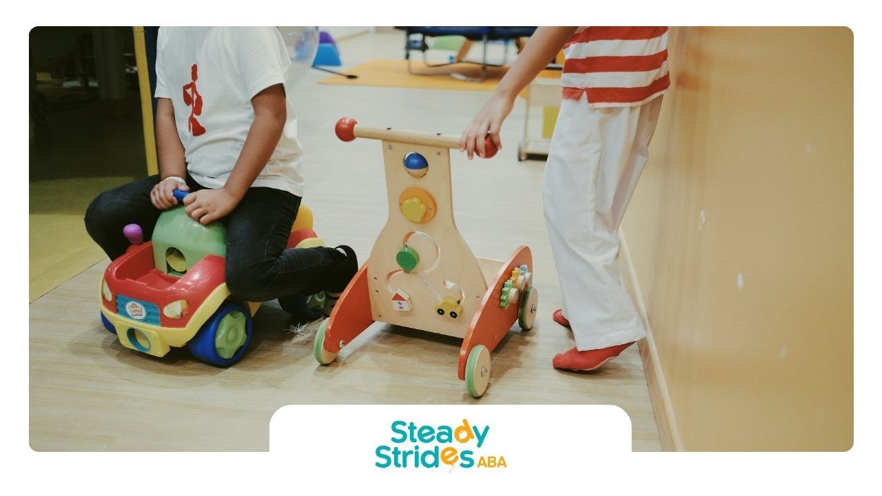 Two utistic children playing with ride-on and push toys during a daycare-based ABA therapy in TX.