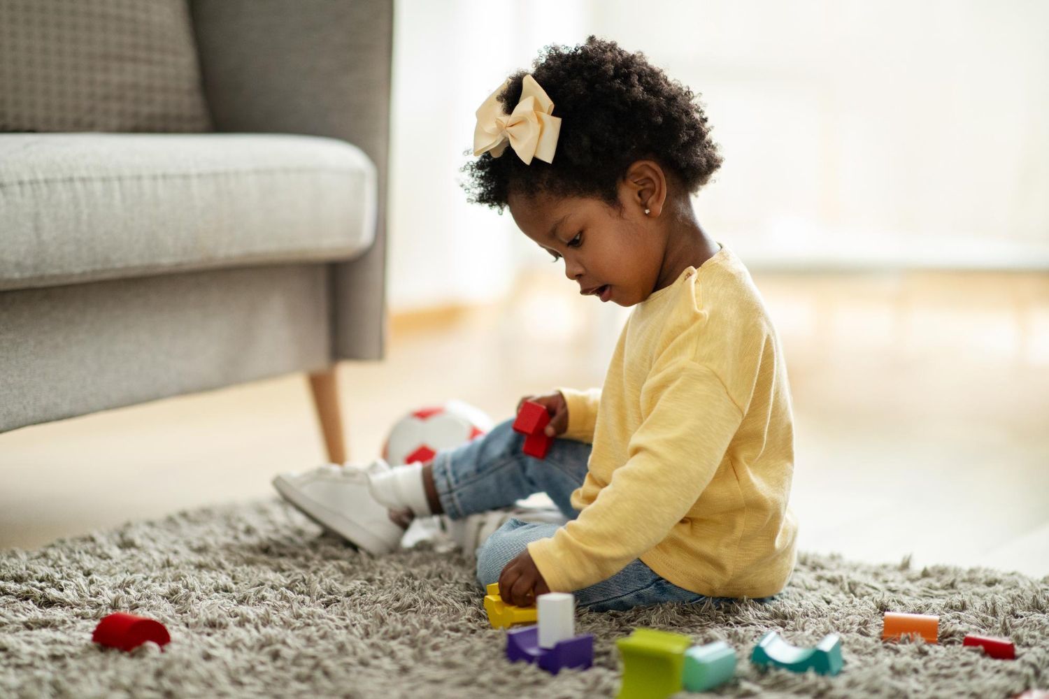 A little girl is sitting on the floor playing with toys.