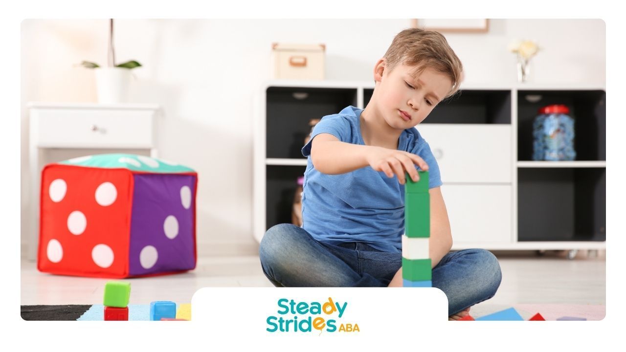 A young boy is sitting on the floor playing with blocks.