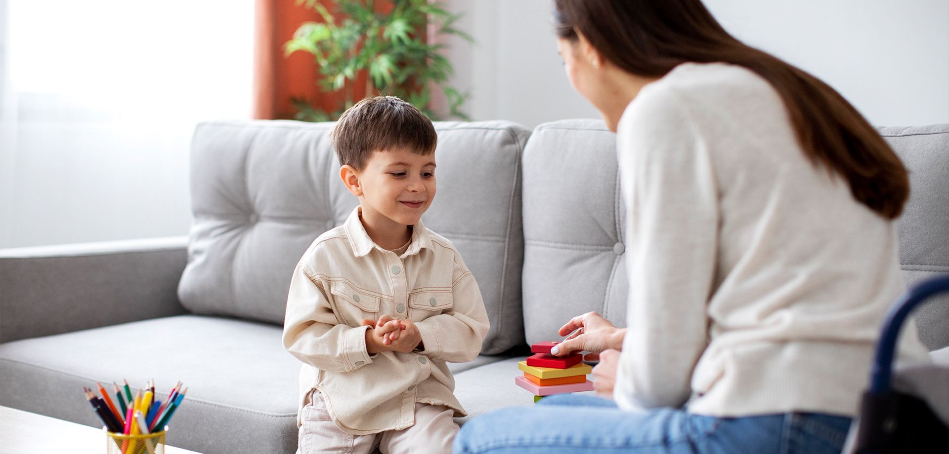 A woman sitting on a couch talking to a young boy.