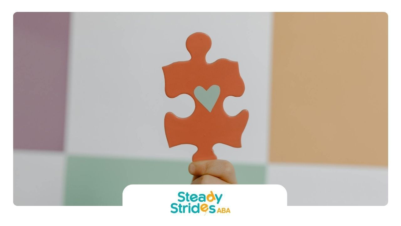 Hand holding a red puzzle piece with a heart in the center, symbolizing autism awareness in Texas.