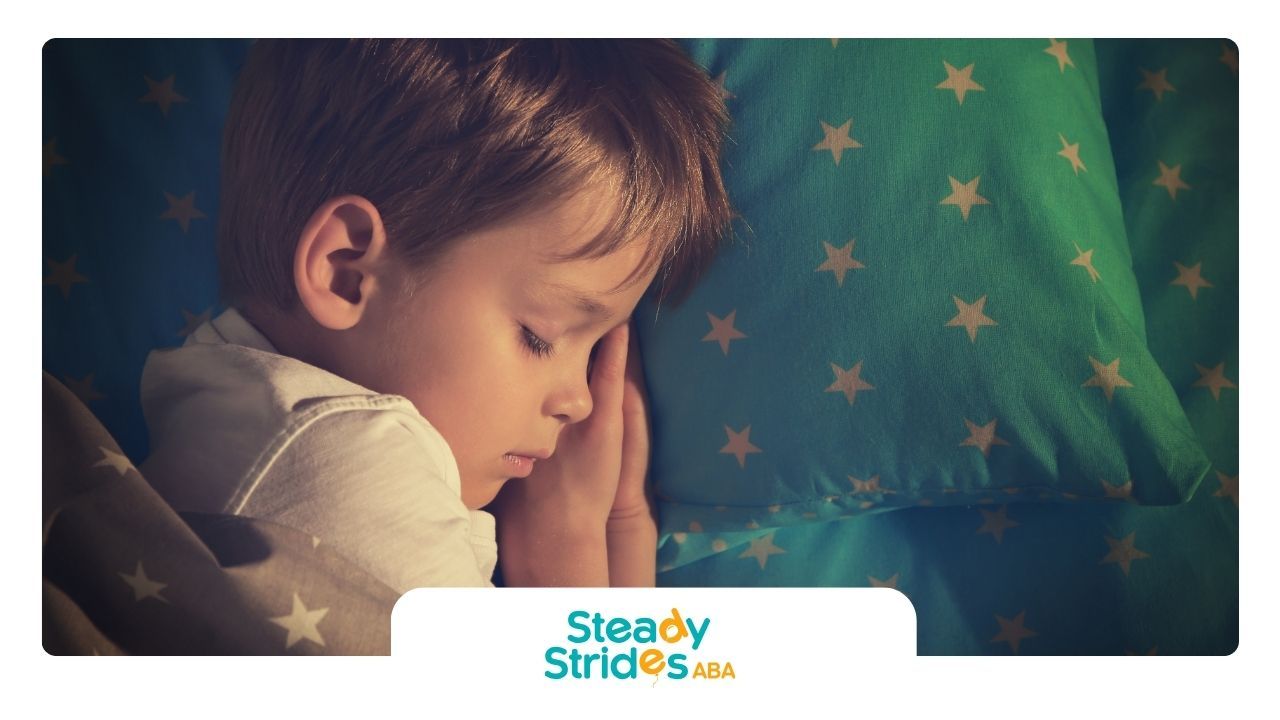 A young boy is sleeping on a bed with a green pillow with stars on it.