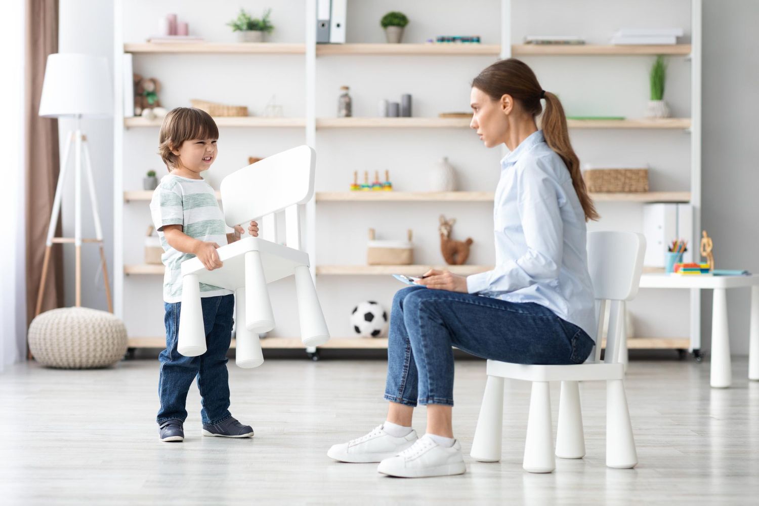 A woman sitting on a chair next to a child standing