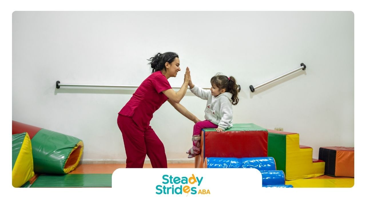 A woman and a little girl are giving each other a high five in a gym.