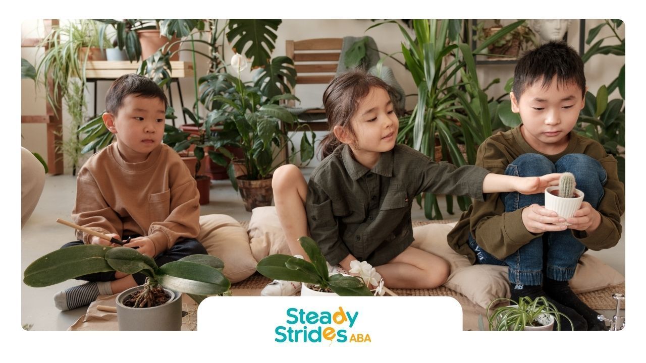 Three children are sitting on the floor with potted plants.