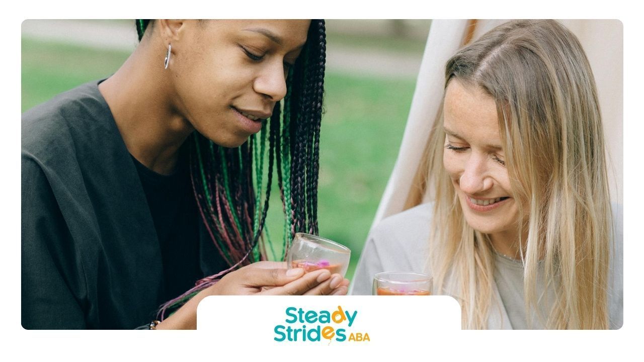 Two adult women, showing signs of autism, smiling and enjoying tea together outdoors in Texas.