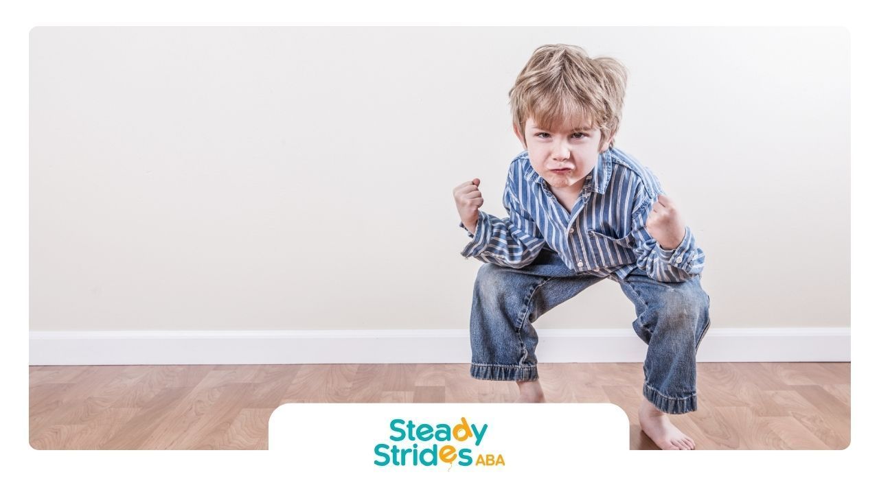 A young boy is squatting down on a wooden floor.