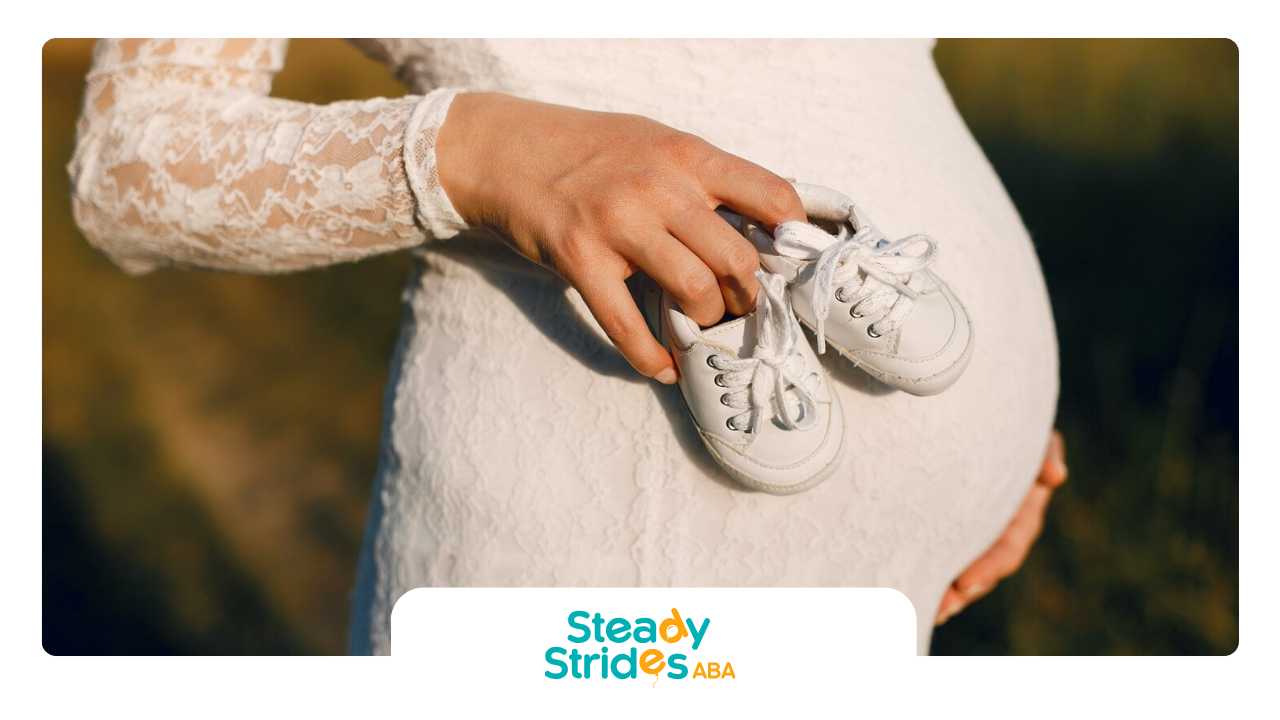 A pregnant woman holding baby shoes