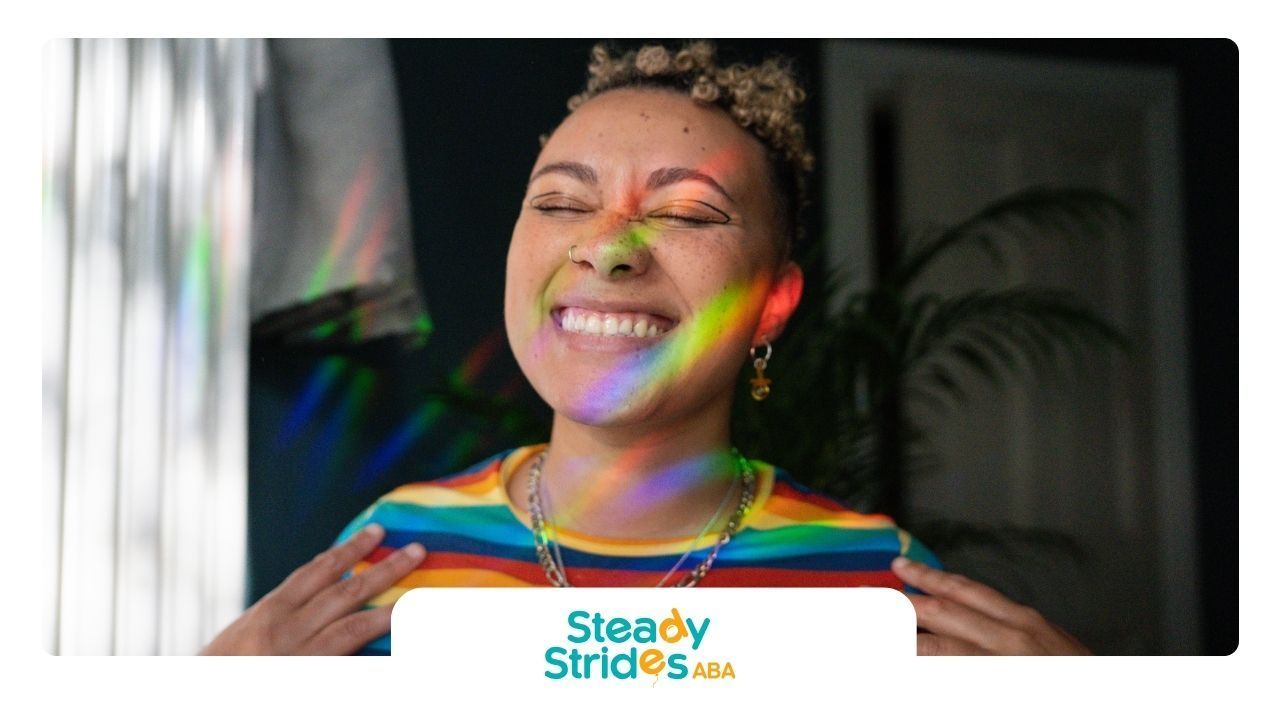 A woman is smiling with a rainbow behind her.