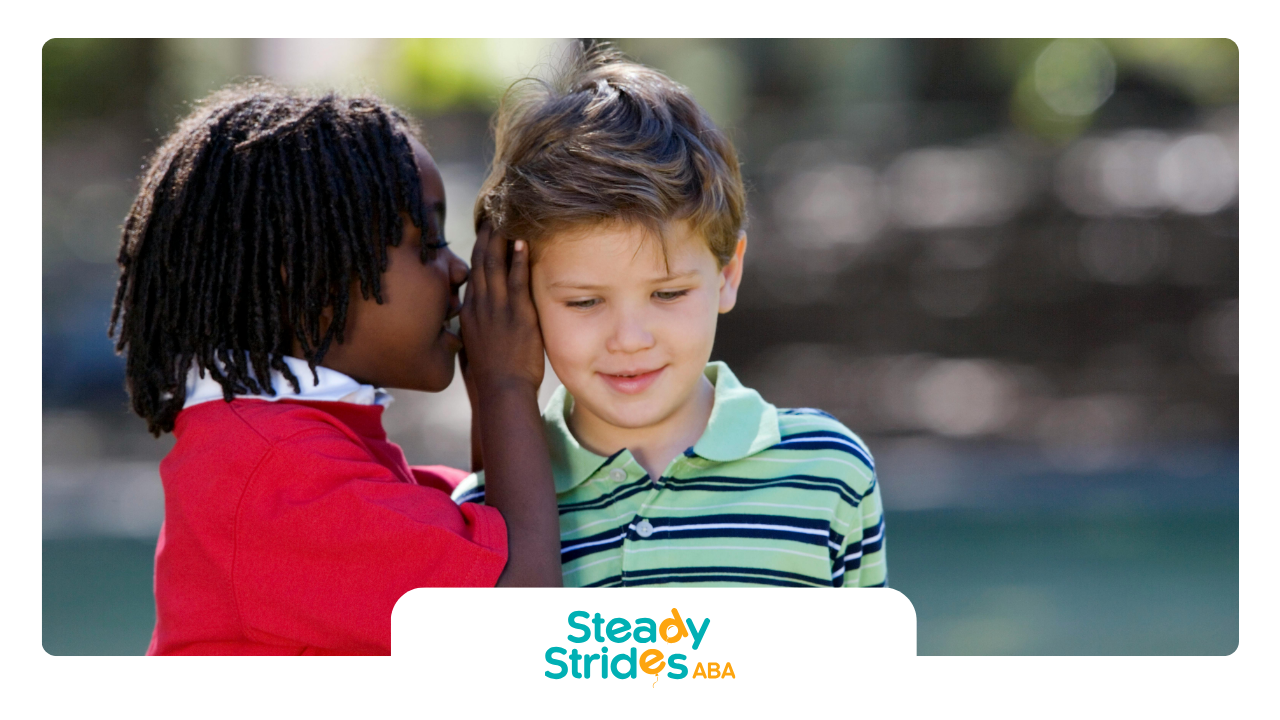 Black child whispers in the ear of a light-skinned child outside.