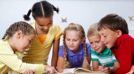 A group of children looking at a book together 
