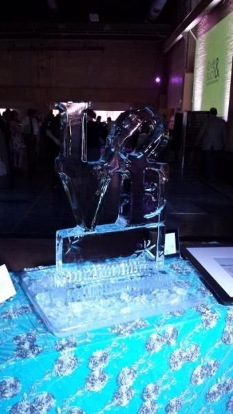 Ice sculpture on a blue-lit table at an indoor event, with purple lighting in the background