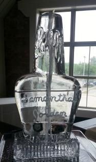 Clear glass bottle in a window, with embossed text and a ribbed base on a tabletop.