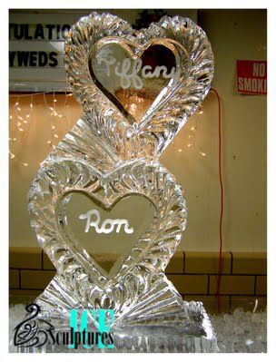 Silver heart-shaped sculpture with two heart cutouts and cursive names inside, displayed indoors.