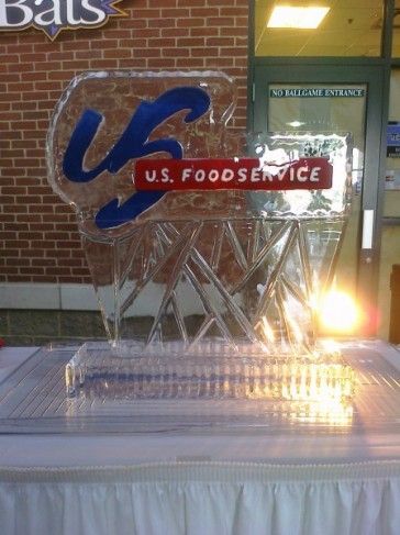 Ice sculpture with blue and red U.S. Foodservice logo at an event table.