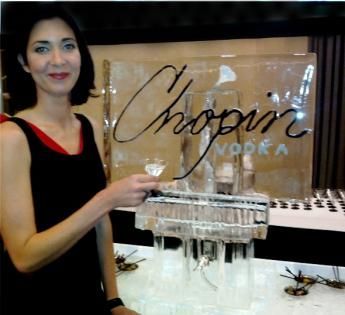 Woman holding a glass beside an ice sculpture and “Chopin Vodka” display at an event