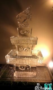 Stacked transparent glass sculptures with etched designs on a lit display table