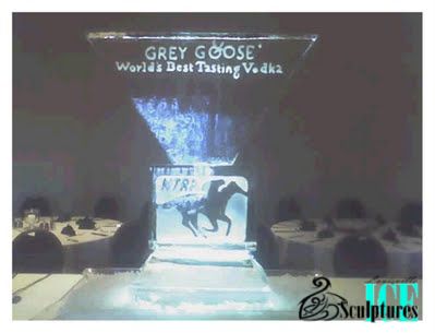 Grey Goose event display with blue-lit ice sculpture and table settings on a dim stage
