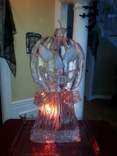 Glass pumpkin-shaped lamp glowing orange on a table in a dim room