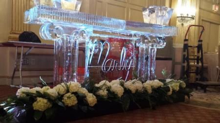 Clear acrylic wedding podium with white floral arrangements in a decorated indoor venue