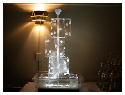 Transparent ice fountain sculpture lit by a warm lamp in a dark room