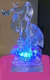 Blue-lit glass bird figurine on a pink cloth against a dark background