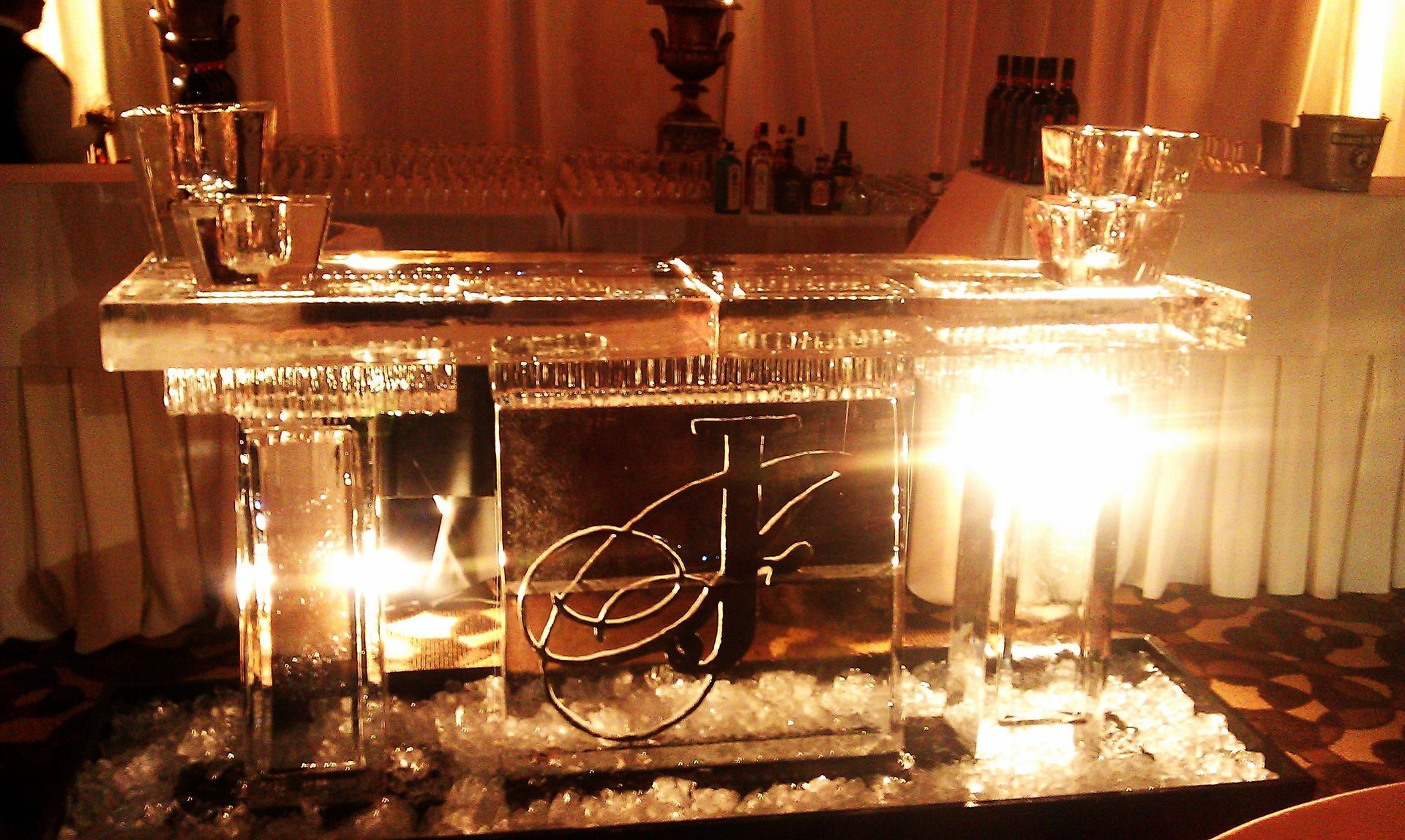 Clear acrylic podium lit by warm candles at an elegant indoor event, with draped curtains behind.