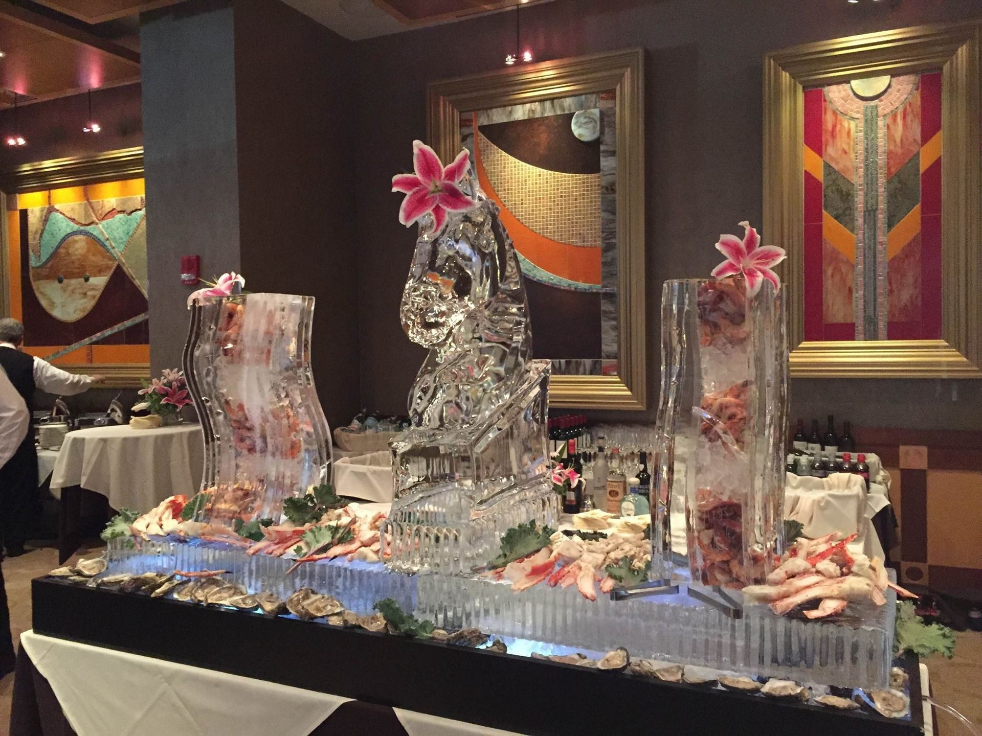 Ice sculpture centerpiece with pink flowers on a banquet table in a dimly lit restaurant