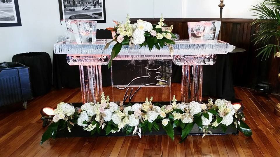 Decorated glass table with white floral arrangements and greenery in a room with wooden floors