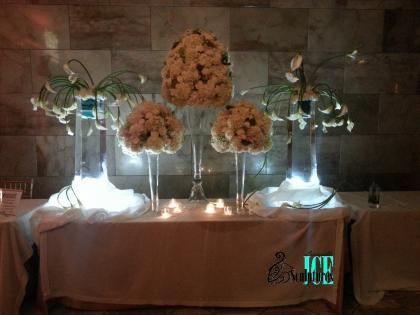 Elegant floral wedding table display with white flowers, glass vases, and soft glowing lights