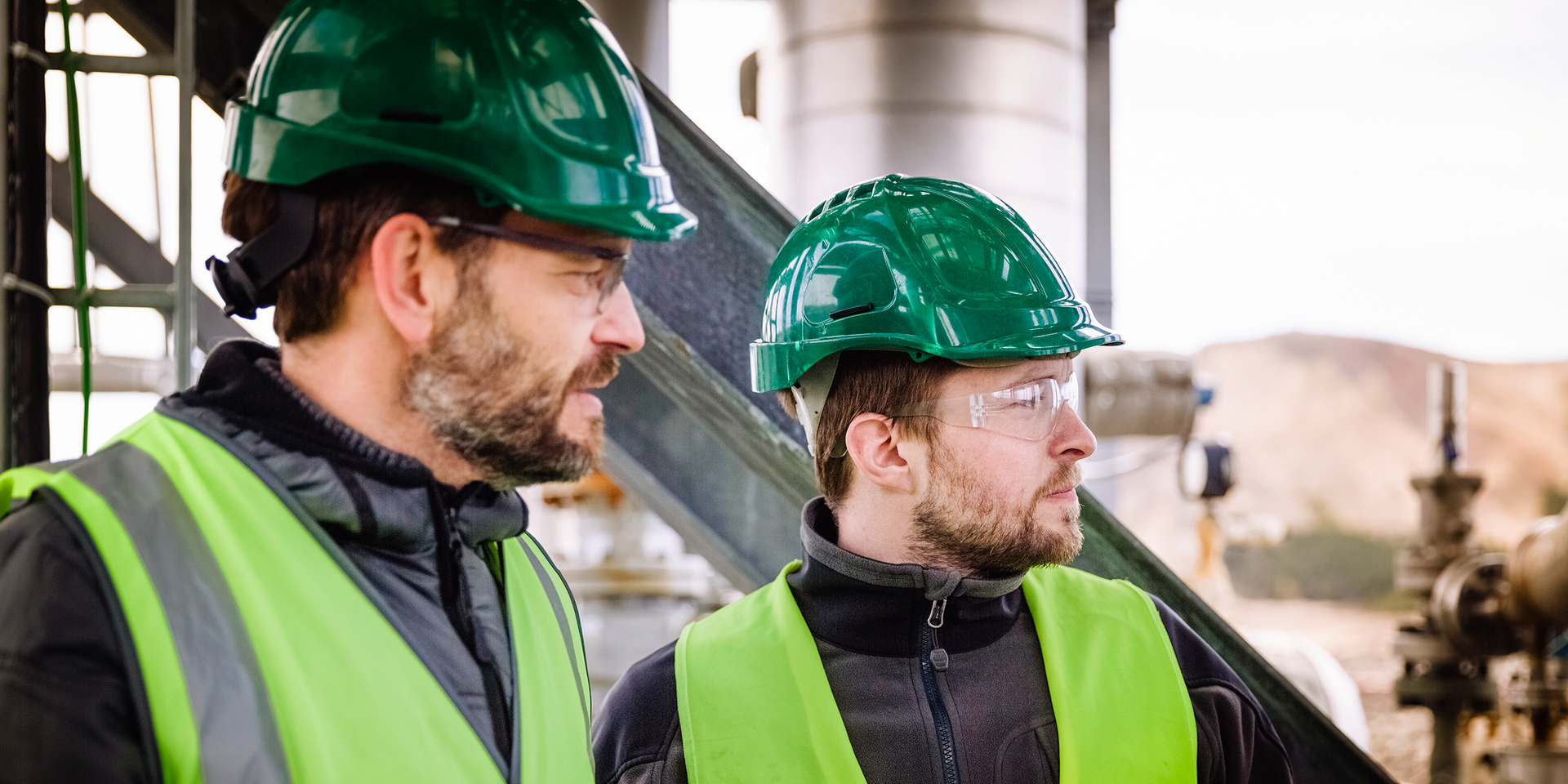 Two electrical workers look off into the distance