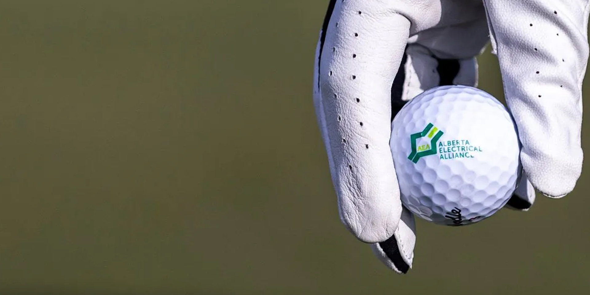 A hand wearing a golf glove places a ball on a tee