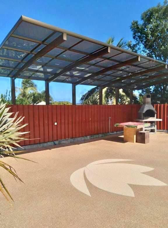 Un patio avec une table et un grill sous un auvent