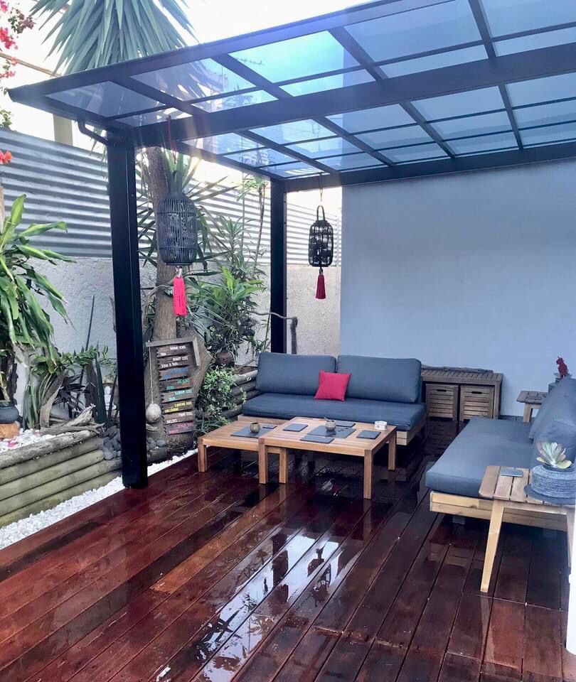 Un salon avec un canapé et une table sous une pergola.