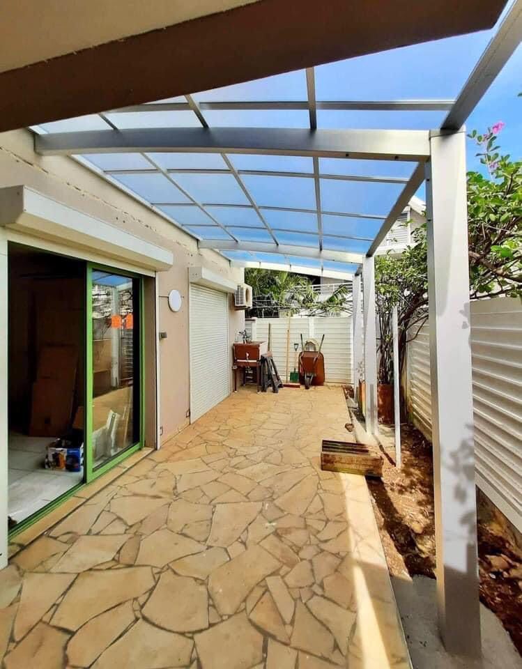 Un patio avec un auvent au-dessus et une porte coulissante en verre.