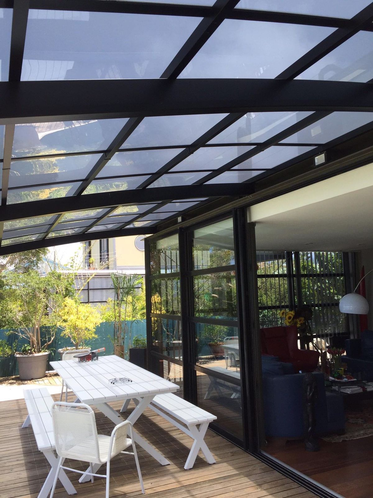 Un patio avec une table et des chaises sous une verrière.