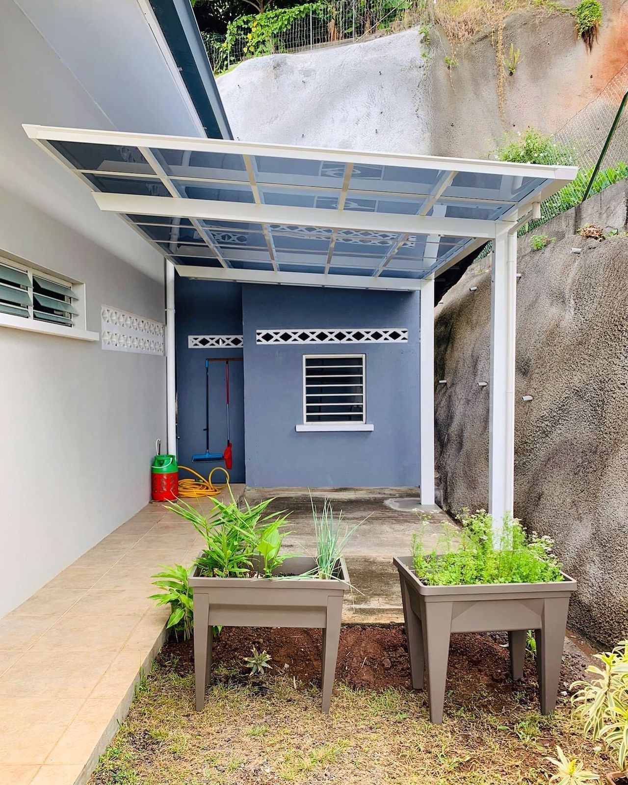 Une maison avec une pergola et des jardinières devant.