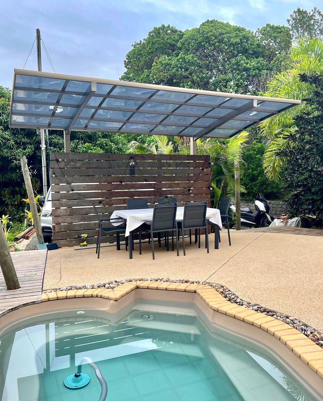 Une piscine avec une table et des chaises sous un auvent.