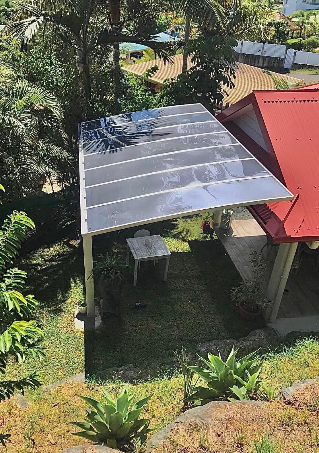 Une vue aérienne d'une pergola avec un toit rouge et une table et des chaises en dessous.