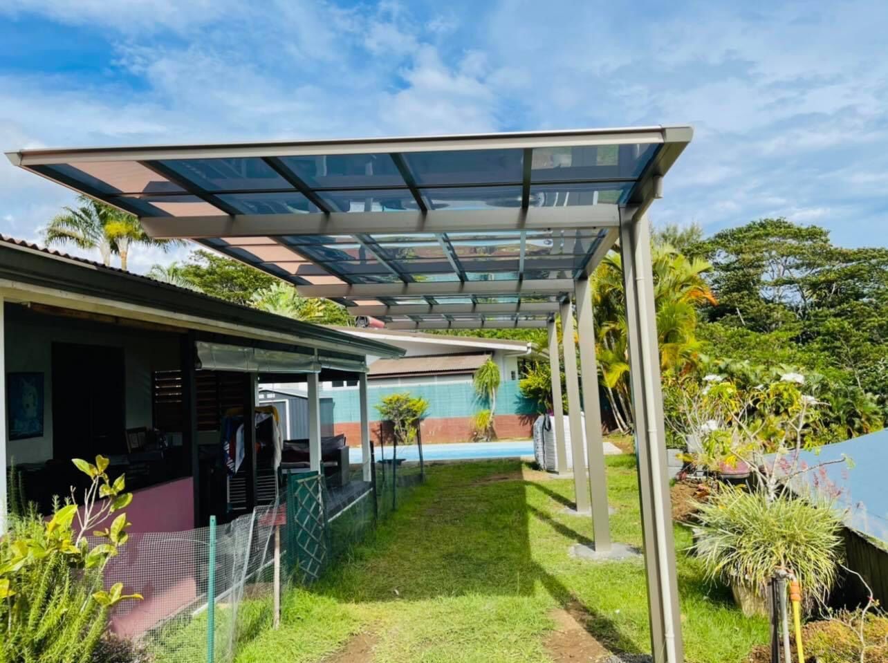 Un passage couvert menant à une maison avec une piscine en arrière-plan.