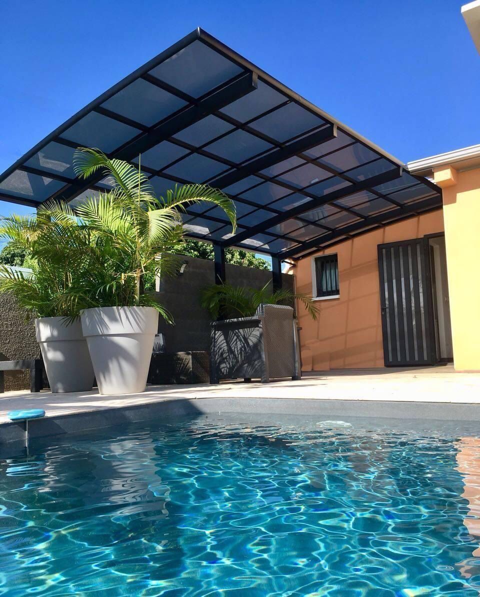 Une piscine avec un auvent au-dessus et une maison en arrière-plan