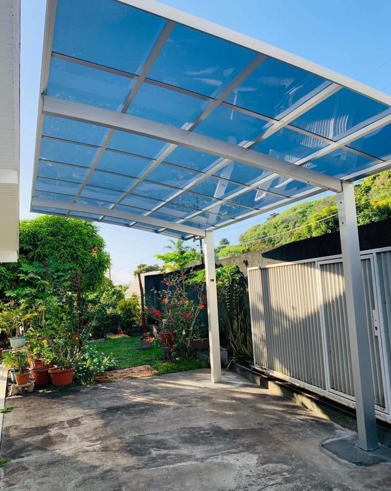 Un abri d'auto avec un toit bleu et une clôture en arrière-plan.