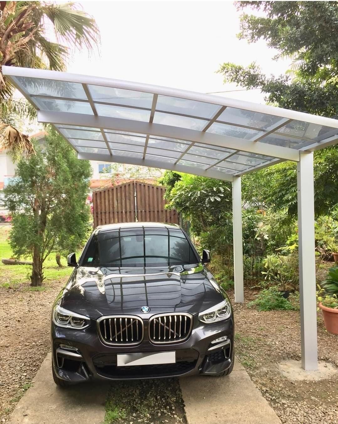 Une voiture est garée sous un auvent dans une allée.