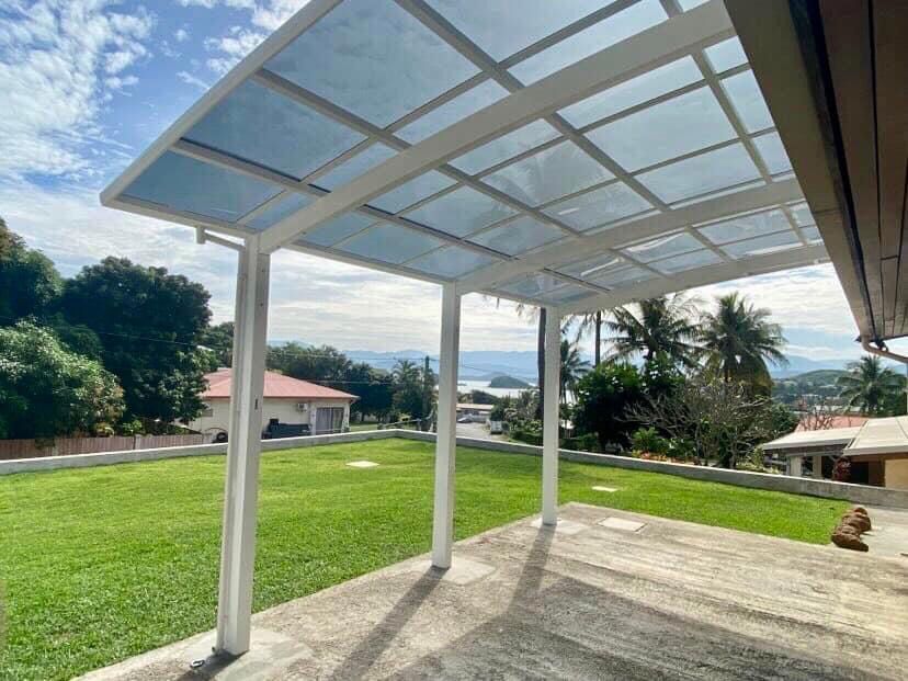 Un patio avec un auvent au-dessus et un champ vert luxuriant en arrière-plan.