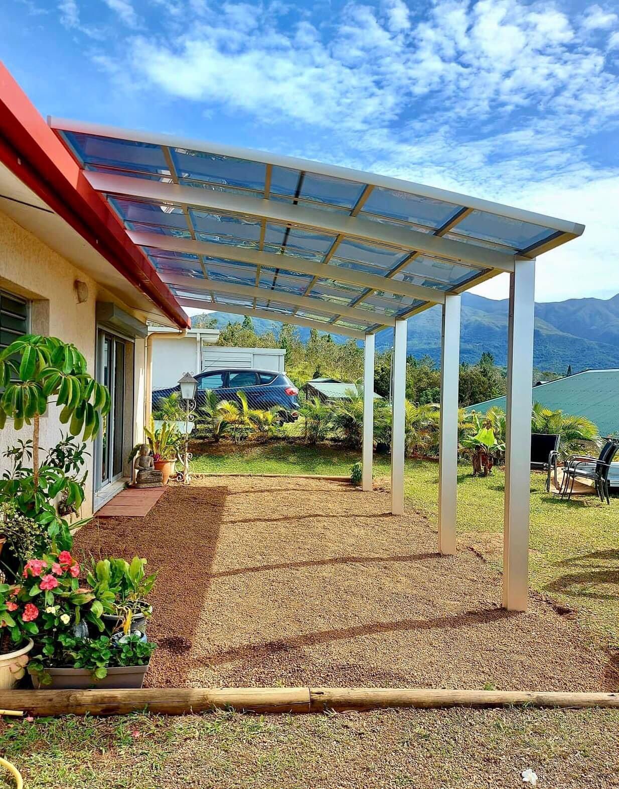 Une maison avec un patio couvert devant elle.